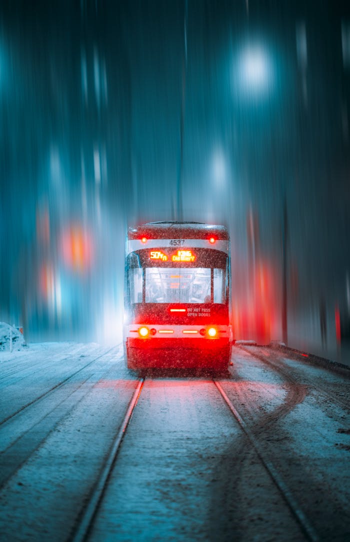 services-02 A Toronto streetcar navigating a snowy street on a vibrant winter night, illuminating the scene with blurred motion.