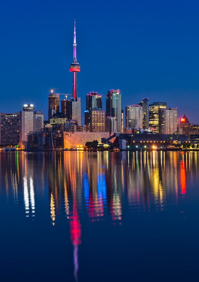 services-03 Beautiful nighttime view of Toronto skyline and CN Tower reflecting on calm water.