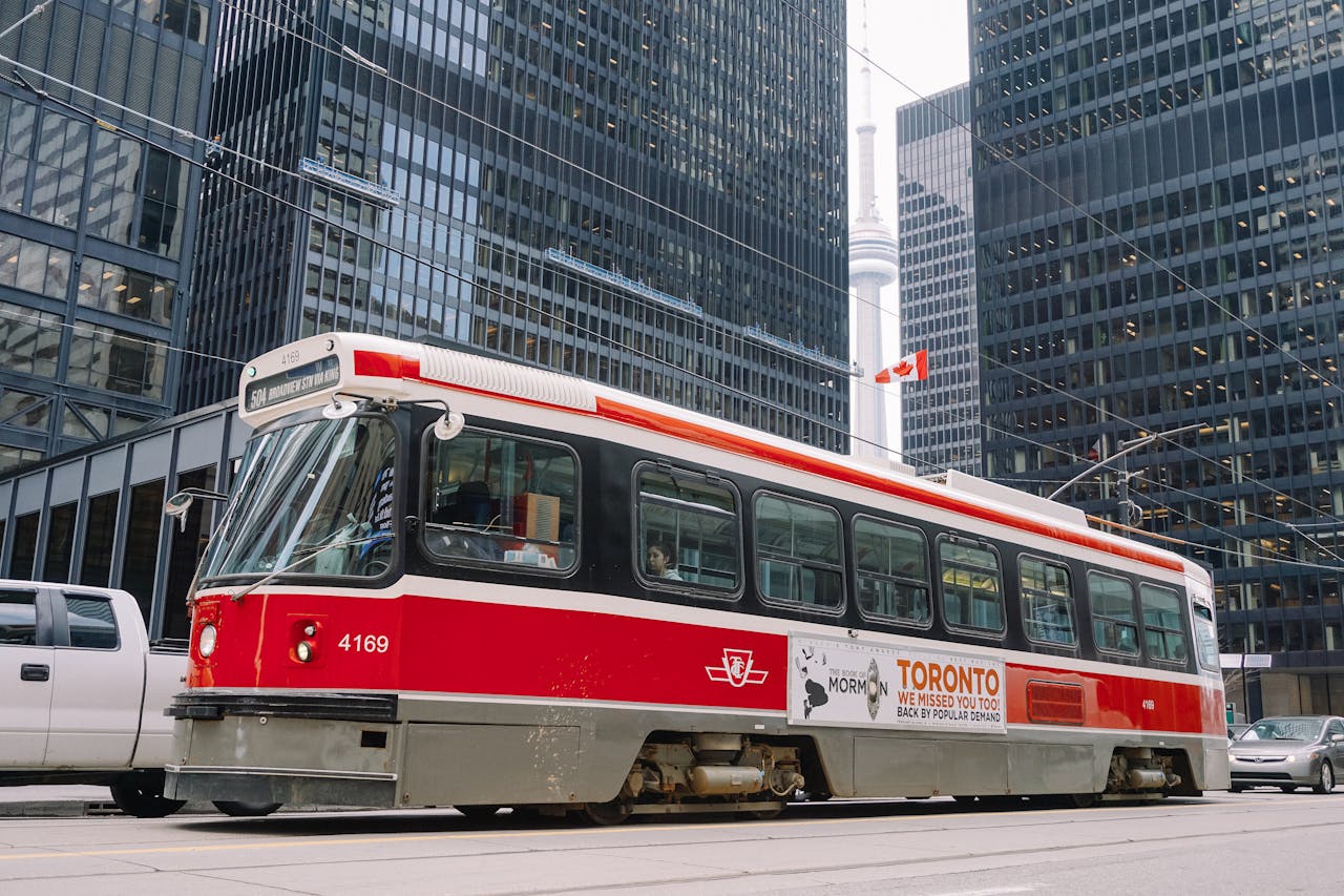 about-us Red public tram on railroad in middle of megapolis roadway surrounded with high rise buildings